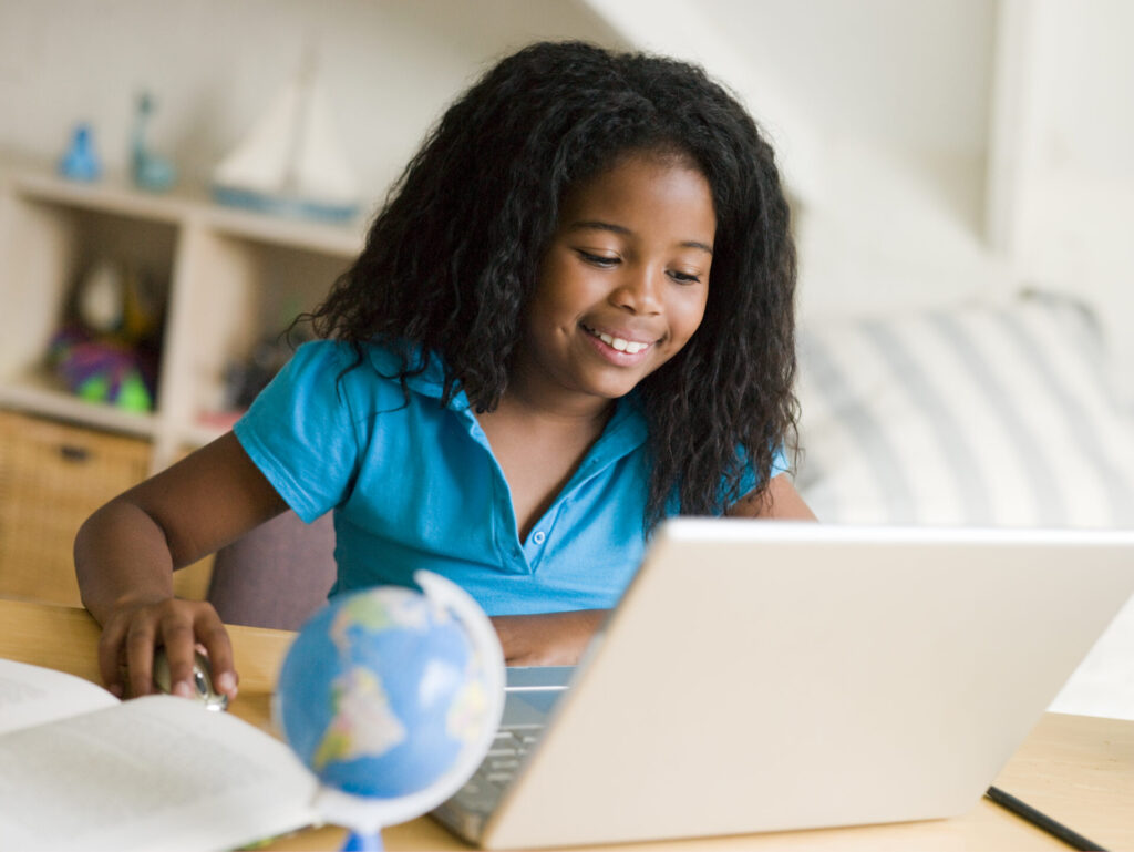 Little Girl Studying on Her Laptop with a globe