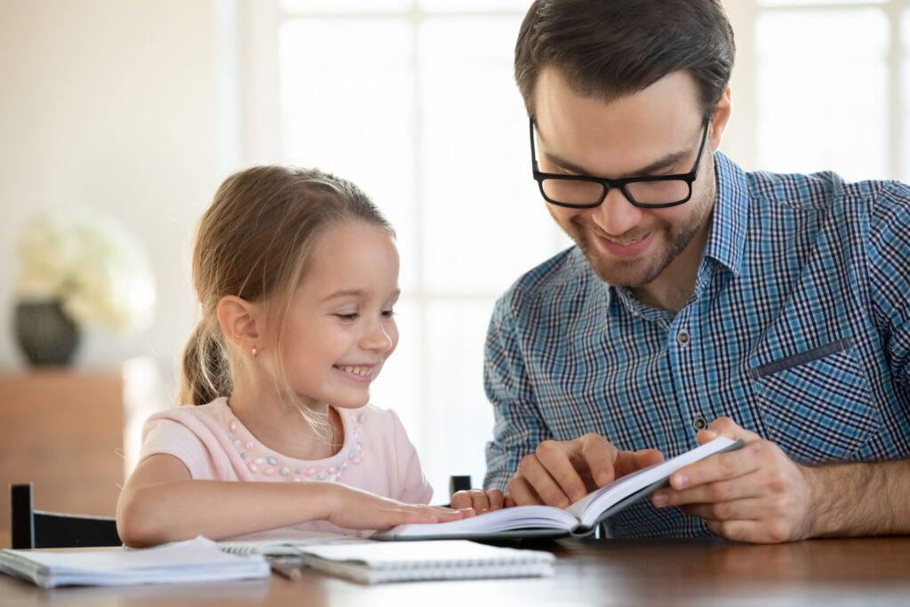 Happy dad and little daughter study reading book